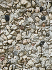 Close-up of a textured stone wall made of pebbles and cement.