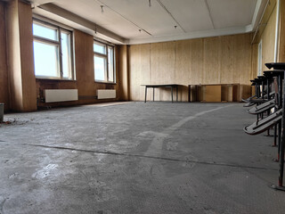 An abandoned room with worn concrete floors and weathered wooden walls.