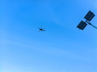 A helicopter soars through a clear, blue sky near solar panels, evoking themes of progress.
