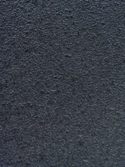 A detailed close-up of a dark, textured and grainy surface, with a subtle pattern