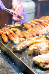 Juicy slices of grilled wild boar meat being roasted over open flames at a night market food stall. The smoky aroma and charred edges highlight the rustic and flavorful appeal of traditional street cu