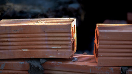 A close-up of two red bricks with a dark gap between them on a construction site. A graphic, abstract, and conceptual image symbolizing connection, separation, or a missing piece.

