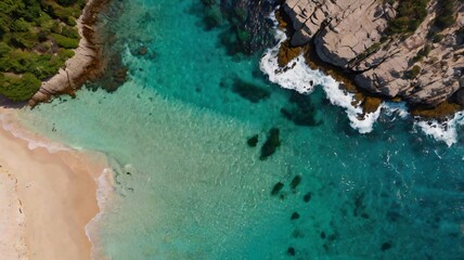 Breathtaking aerial view of a pristine beach with clear turquoise waters, rocky cliffs, and lush vegetation. Ideal for serene landscapes, travel themes, and nature appreciation.