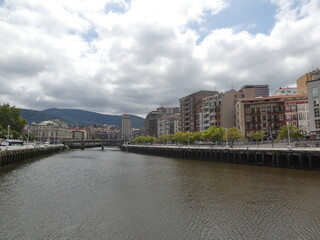 Naklejka premium Vista del río Nervión cruzando un puente con edificios de Bilbao al fondo