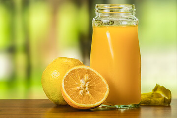 Fresh orange juice in a glass, with a blurry green background.