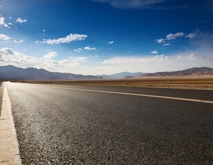 Fototapeta premium empty asphalt under a blue sky and rolling mountains in the distance
