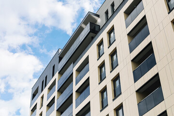 Modern residential apartment building. Facade with balconies and windows. Urban housing architecture. New real estate development. Contemporary city lifestyle. Cloudy sky in background. Urban growth.