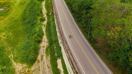 Fototapeta premium Aerial view of a road in the middle of the forest. Top view of asphalt road through forest with car adventure. Healthy environment road trip travel. 