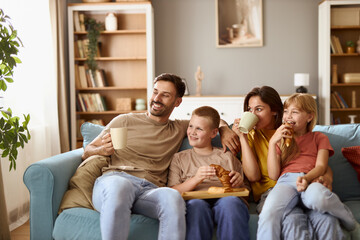 Happy parents and their kids day dreaming while relaxing on sofa at home.