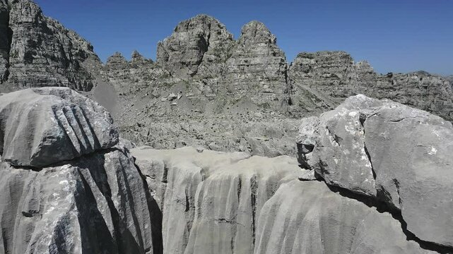A drone rises above sharp cliffs, revealing a unique panorama of the gray rock valley of Mount Maganik and Mount Babin Zub in Montenegro