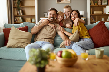 Happy family relaxing on sofa in the living room and looking at camera.