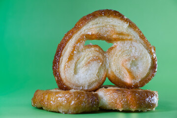 Palmier puff pastries balancing on green background