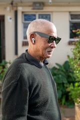 Senior man seen with pods and sunglasses on