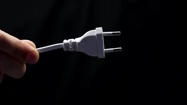 Electrical cable and plug in the hands of a man on a black background.
Man holding an electrical cable in his hands