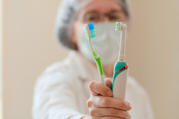 A professional dentist holding both an electric and a manual toothbrush provides insight on dental hygiene. A reminder that proper care starts with the right tools and consistent brushing.