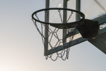 Outdoor basketball hoop with backboard, metal rim and chains, glass or acrylic backboard Blue sky...