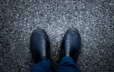 Man feet standing on asphalt road