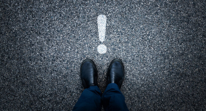 Man standing on asphalt road with exclamation point