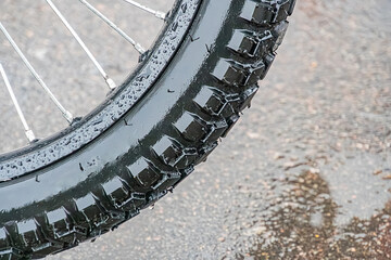Close-up of a postal electric bicycle wheel, focus on black off-road tire with water droplets...