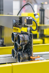 Industrial setting, large yellow-black machine, conveyor system or assembly line, rotating cylinder...