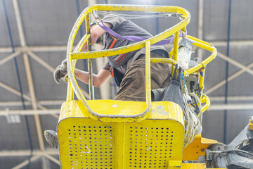 Industrial forklift operation in a spacious, high-ceilinged facility Yellow forklift with orange...