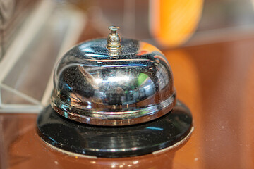 Overhead shot of polished brown surface, old-fashioned brass elevator bell with reflective top and...