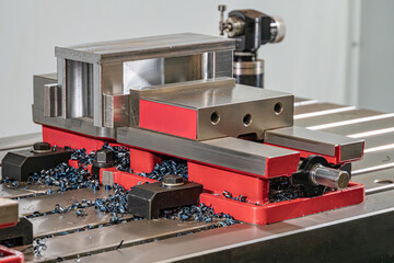 An industrial scene featuring a red and silver machinery fixture, possibly part of a manufacturing...