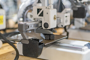 Close-up of an industrial workspace featuring a metal robotic arm with gripper, focused on a metallic object Computer monitor nearby displays data Overhead lights cast shadows Automated manufactur