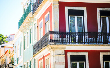 Naklejka premium Colorful traditional European buildings with wrought iron balconies in bright sunlight. A vibrant urban scene showcasing architectural details, pastel facades, and historic charm