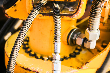 Macro shot of hydraulic hoses and metal connectors on industrial machinery. Detailed view of...
