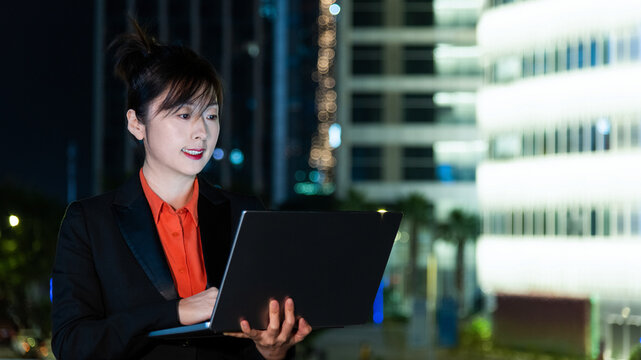 Woman using laptop outdoors at night