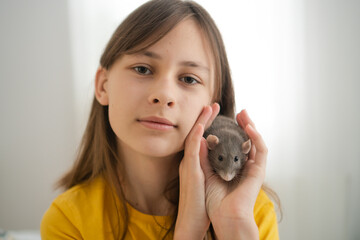 Adolescent female gently interacting with her domesticated gray rat. Tender display of animal friendship and responsible pet ownership.