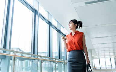 Businesswoman using phone and walking on office corridor
