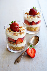 Delightful Strawberry Parfaits Layered in Clear Glasses with Cream and Crumbled Cake, Topped with Fresh Strawberries and Almonds, Presented on a Rustic Wooden Surface, Showcasing a Delicious Dessert