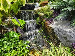 A beautiful waterfall in a garden, surrounded by lush plants