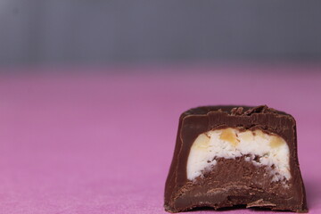 Chocolate candy with praline and pieces of walnut on a pink background close-up with space for...