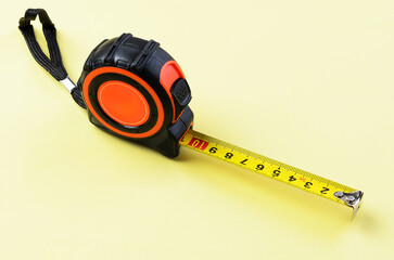 Construction measuring tape on bright yellow background isolated closeup tool image