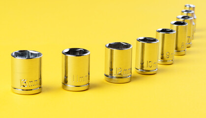 Hexagonal socket wrench attachments set 13mm and smaller on yellow background