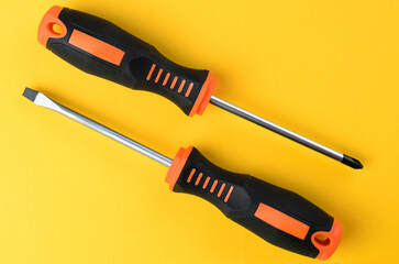 Cross and flat screwdrivers on bright yellow background isolated closeup tools