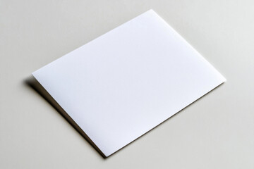 A blank white postcard lying flat on a white surface, with soft shadows on the edges. 