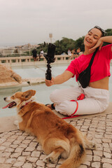 Young girl with Corgi recording video on phone share via app her travel vacation. Gen Z influencer...