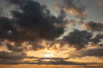 Cloudy sunset background backdrop with the sun rays breaking through the clouds.