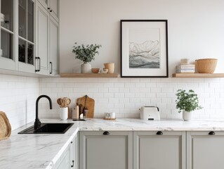 A kitchen with a white countertop and cabinets. A framed picture of mountains is on the wall. A sink is on the left side of the counter