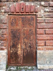 Antique metal door with peeling paint in an old red brick house. Retro style