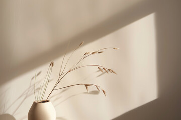 Minimalist vase with dried grasses, casting a soft shadow on a muted wall. Simple, elegant, and...
