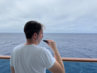 Cruise Ship Morning Routine: Brushing Teeth with electric toothbrush and overcast ocean view 