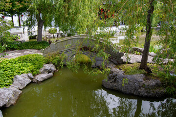 Tranquil Garden with Stone Bridge and Reflective Pond