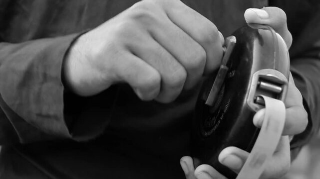 tape measure, old version since 1989. Construction tape measure, length measurement. A teenager twists and inserts a ribbon with his hand. Black and white science.