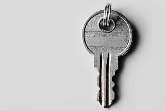 Minimalist view of a simple silver key on a white background, with soft lighting creating a clean, elegant look. 