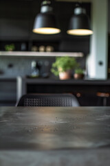 A minimalist kitchen interior with a focus on the black countertop in the foreground. Background details include modern lights, shelves with plants, and a simple, sleek design.